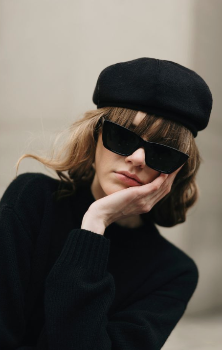 Person wearing a black beret and sunglasses with a neutral background