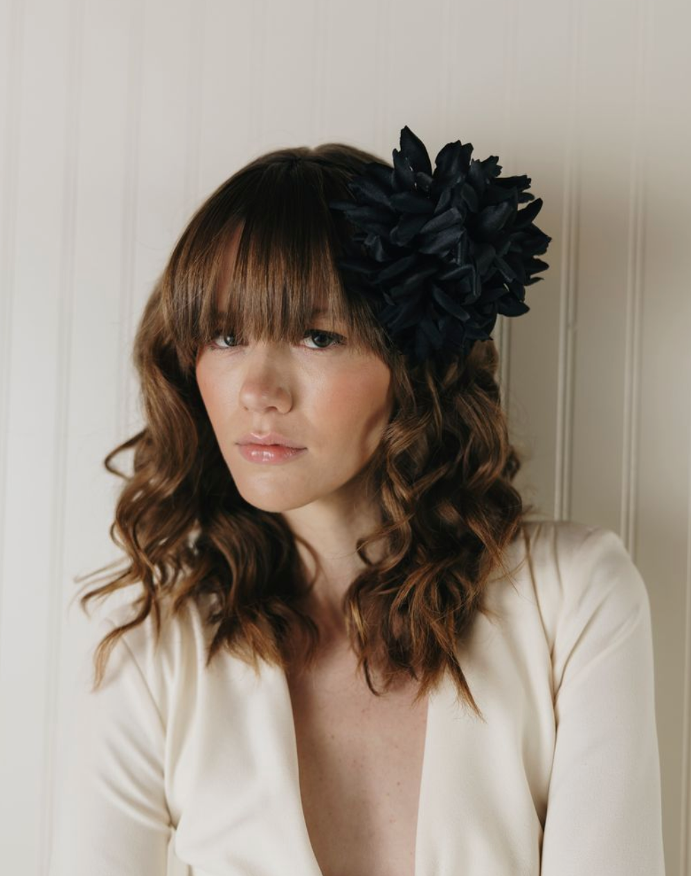 Woman wearing a black floral headpiece against a neutral background