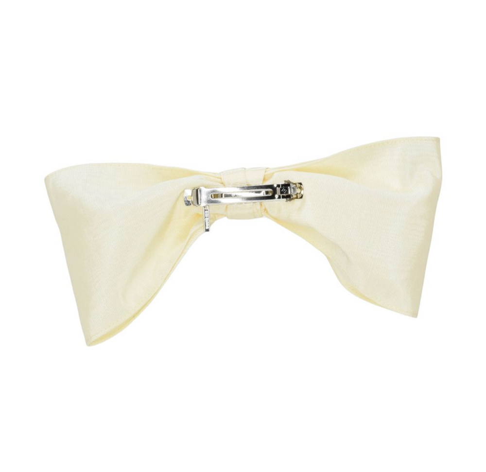 Cream-colored bow hair clip on a white background